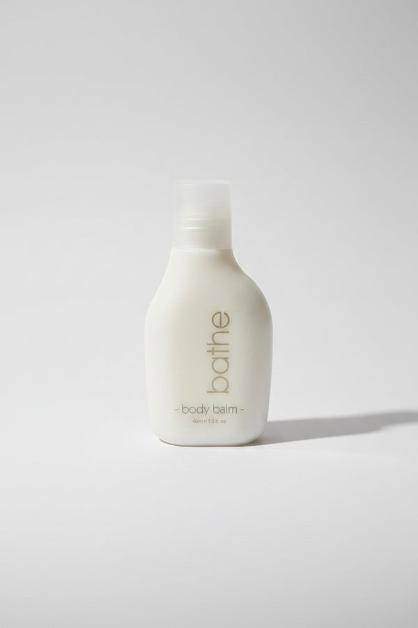 White bottle of 'bathe' body balm on a light gray background