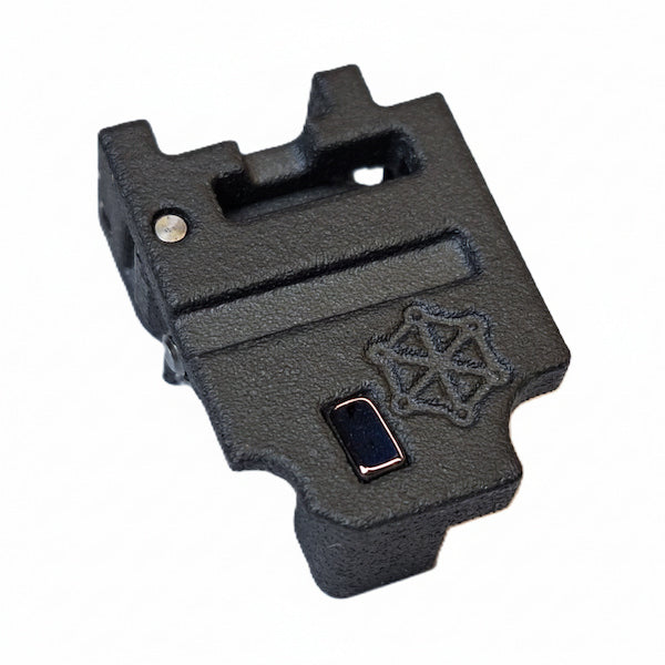 A black textured plastic or metal accessory component with a small rectangular dark insert and an embossed geometric logo, shown on a plain white background.