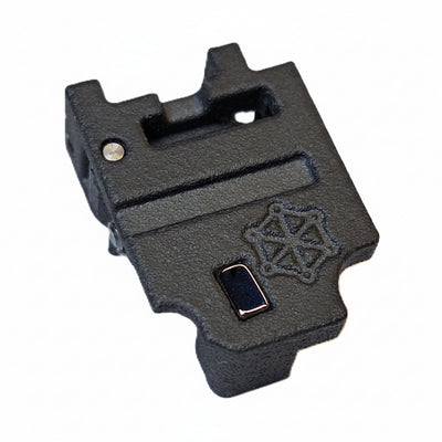 A black textured plastic or metal accessory component with a small rectangular dark insert and an embossed geometric logo, shown on a plain white background.
