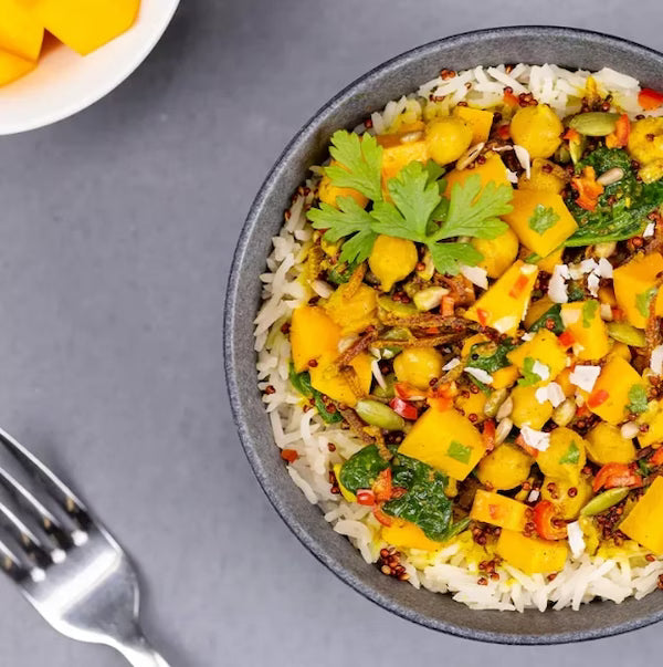 Bowl of rice with yellow vegetable dish on a gray surface