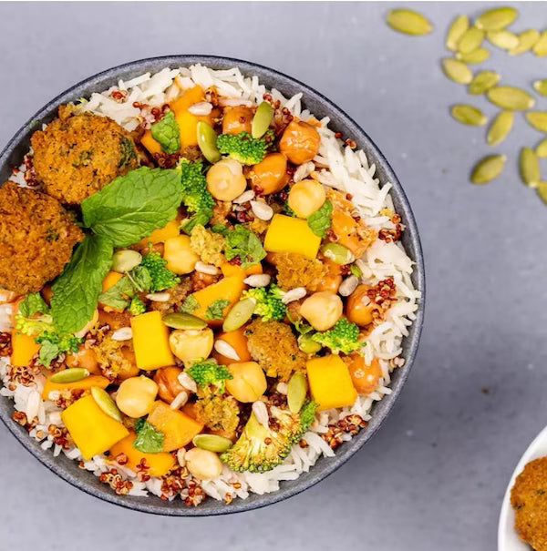 bowl of rice with vegetables and chickpeas on a gray background