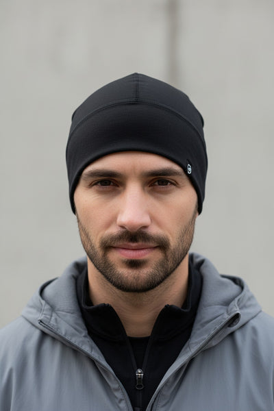 Man wearing a black beanie and gray jacket against a plain background