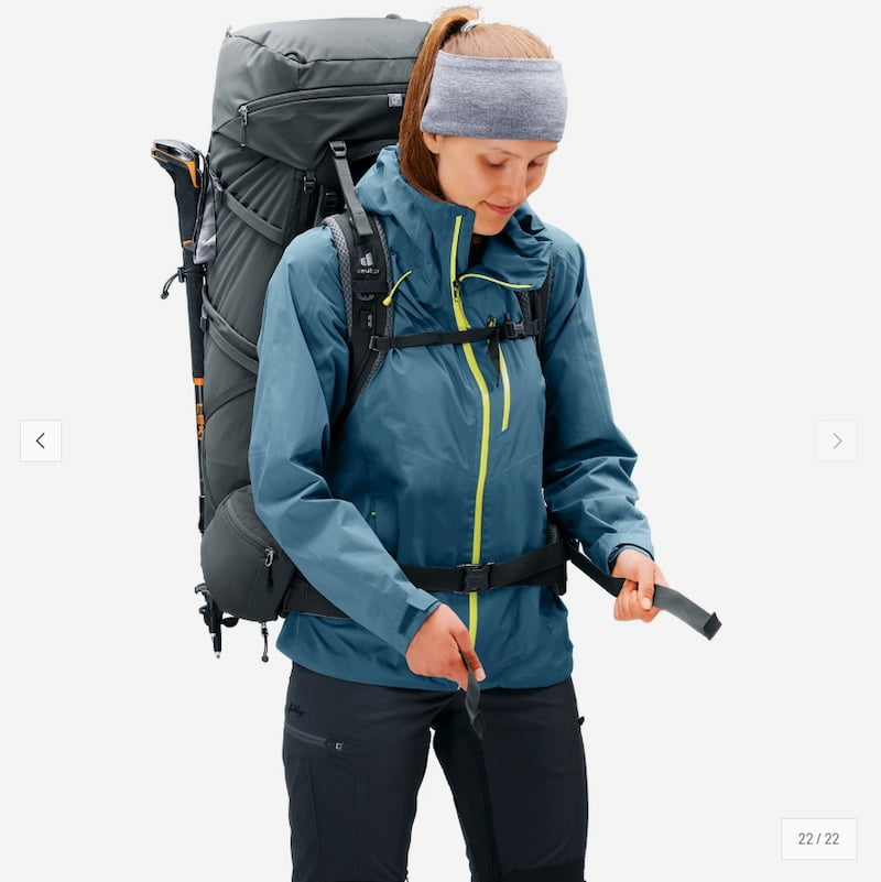 Person wearing a blue jacket and carrying a large gray backpack on a white background