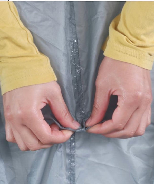Person adjusting a gray raincoat with yellow sleeves