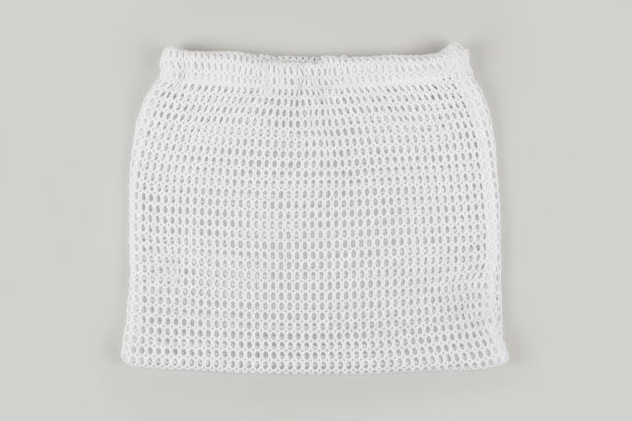 A white open-knit mesh mini skirt with an elastic waistband, shown flat against a solid light gray background.