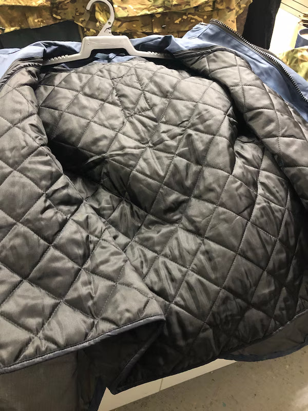 Gray quilted jacket on a hanger with a blurred background