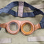 Vintage-style goggles with leather straps on a green fabric background