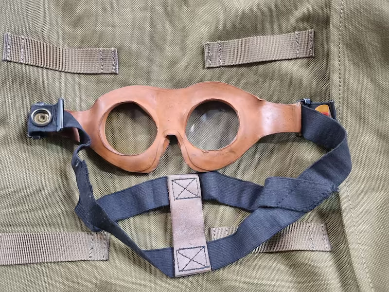 Brown goggles with blue straps on a green fabric background