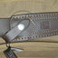 Close-up of a leather sheath on a beige bag with a visible brand logo.