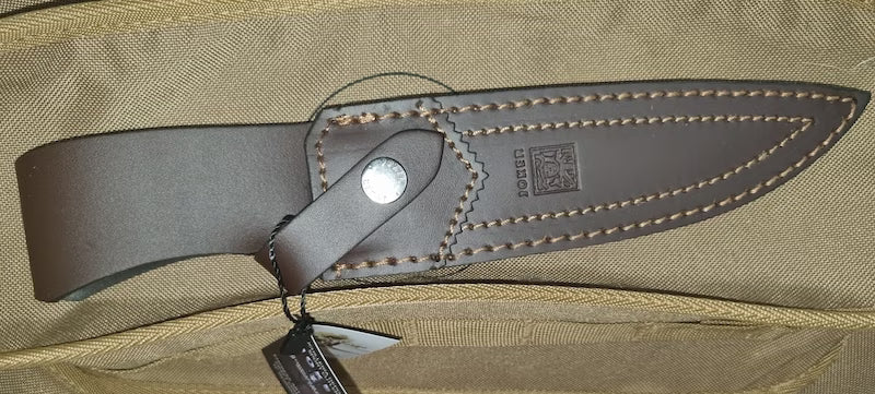Close-up of a leather sheath on a beige bag with a visible brand logo.