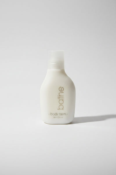 White bottle of 'bathe' body balm on a light gray background