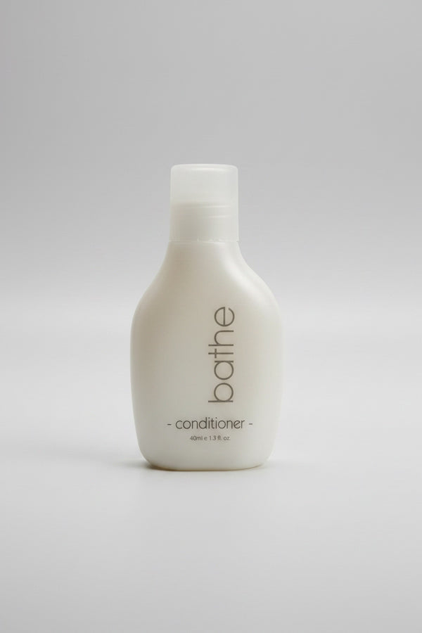White bottle of 'bathe' conditioner on a light gray background