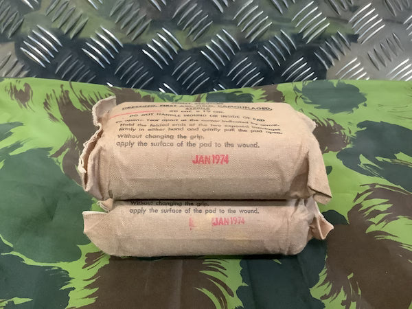 Two bandage rolls with text on a camouflage-patterned surface