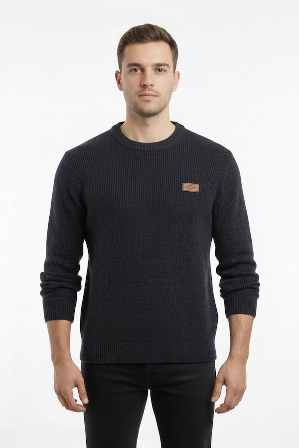 Man wearing a dark blue sweater with a small logo on a white background