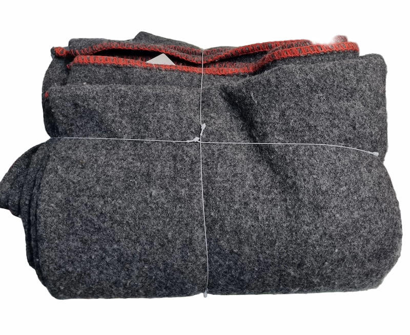 A folded dark gray wool felt blanket or throw with a contrasting red inner lining, secured with white string on a white background.