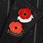 Two enamel poppy badges affixed to a black leather jacket, one larger with the text 'lest we forget' and a smaller version.
