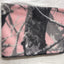 Folded pink and gray camouflage blanket on a white surface