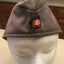 Gray cap with a embroidered badge on a mannequin head against a kitchen background