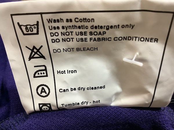 Clothing label with care instructions on a purple fabric background