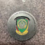 Metallic badge with emblem and text on a textured surface