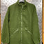 Green fleece jacket on a hanger against a metallic background