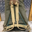 Green backpack with brown straps on a textured surface