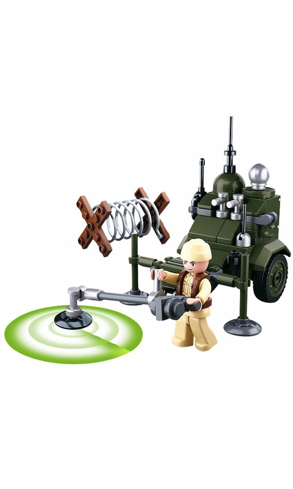 A toy military vehicle set with a small figure, including an olive green armored car, a mounted spring device, a metal detector on a green circular base, and a beige-clad minifigure, shown on a white background.
