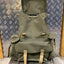 Green backpack with brown straps on a metal surface with a patterned wall background