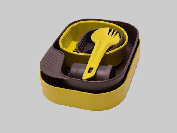 Set of yellow and gray kitchen utensils in a container on a light gray background
