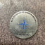 Metallic badge with blue emblem and text on a textured surface