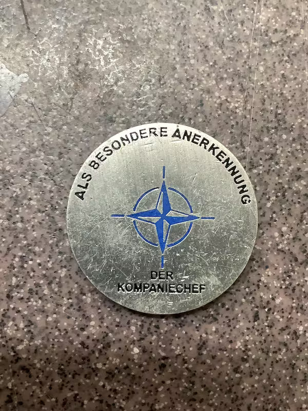 Metallic badge with blue emblem and text on a textured surface