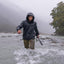 Person wading through a river wearing a raincoat on a foggy day.