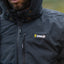 Person wearing a black jacket with a visible brand logo outdoors
