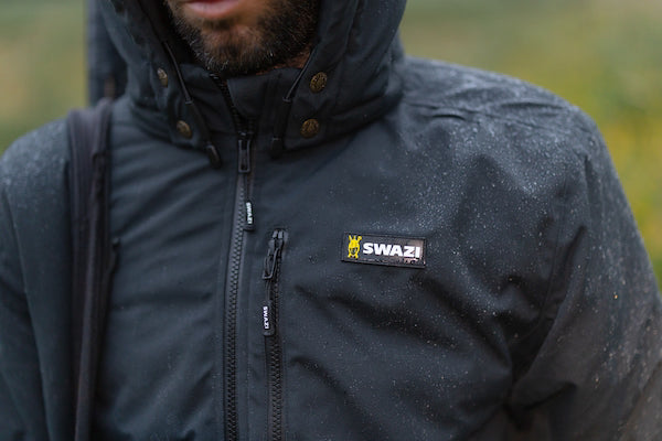 Person wearing a black jacket with a visible brand logo outdoors