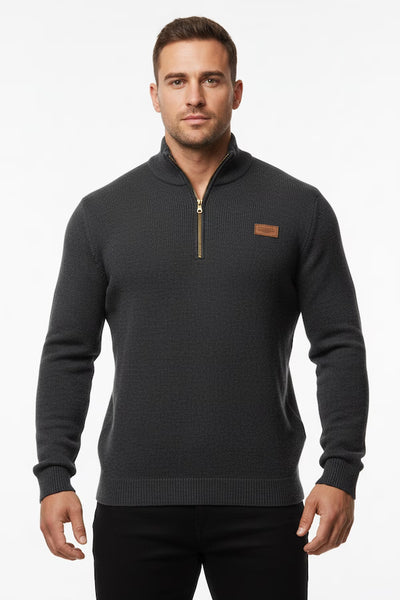 Man wearing a dark gray sweater with a small brown logo on a white background