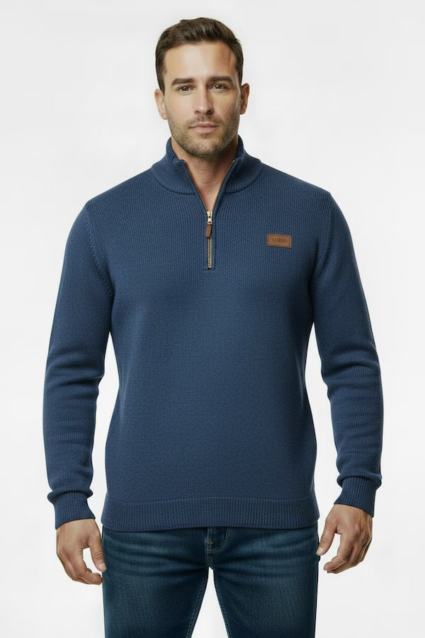 Man wearing a blue sweater with a small brown logo on a white background
