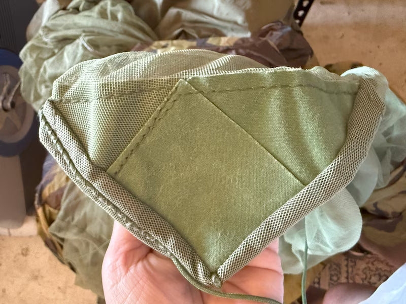 Green fabric face mask held by a hand with a blurred background