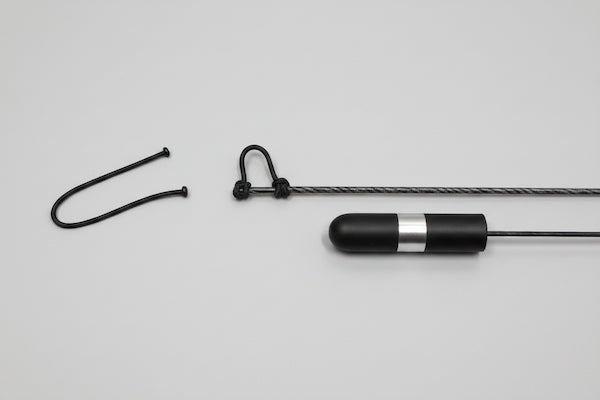 Black and silver cylindrical device with a rope on a gray background