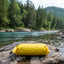 Yellow inflatable raft on a rock by a river with trees in the background