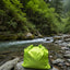 Green drawstring bag on a rock by a forest stream