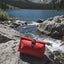 Red pack on a rock with a mountain lake and trees in the background