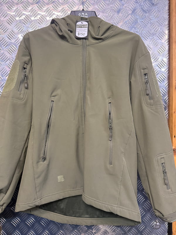 An olive green hooded softshell jacket with multiple zippered pockets, hanging on a black hanger against a textured diamond plate metal background.
