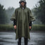 Person wearing a green rain poncho standing in the rain with a blurred background