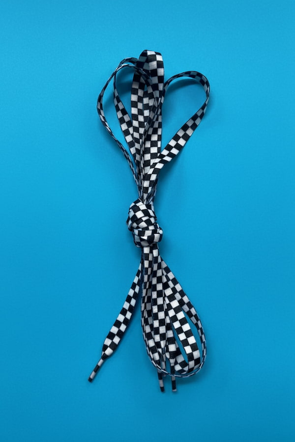 Checkered shoelace tied in a knot on a blue background