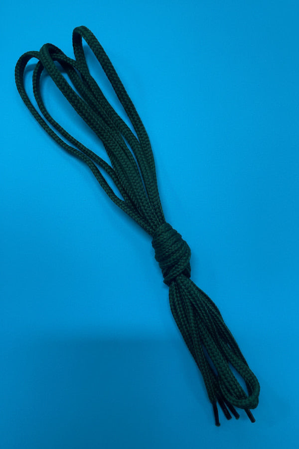 A bundle of dark green braided cord or rope tied in a knot, photographed against a solid blue background.