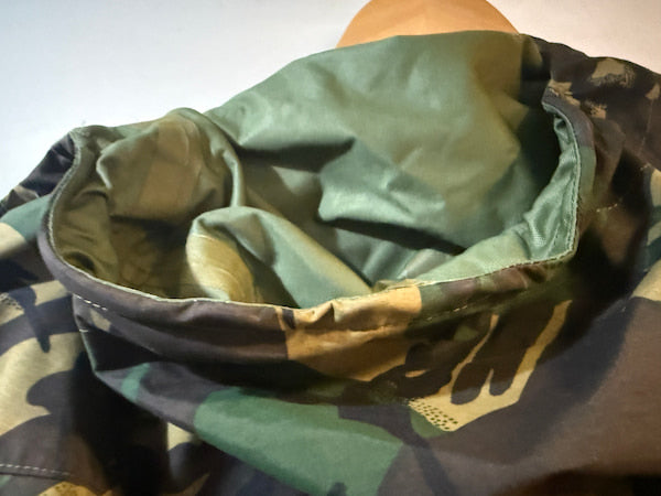 Close-up of a camouflage fabric item, likely a hood or neck warmer, showing the interior lining and pattern details.