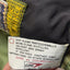 Close-up of a garment's interior care label showing the Gore brand and care instructions, with a dark gray fabric body and a yellow patterned trim.