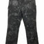 Black and gray camouflage cargo pants with a reptile-scale pattern, hanging on a black hanger against a white background.