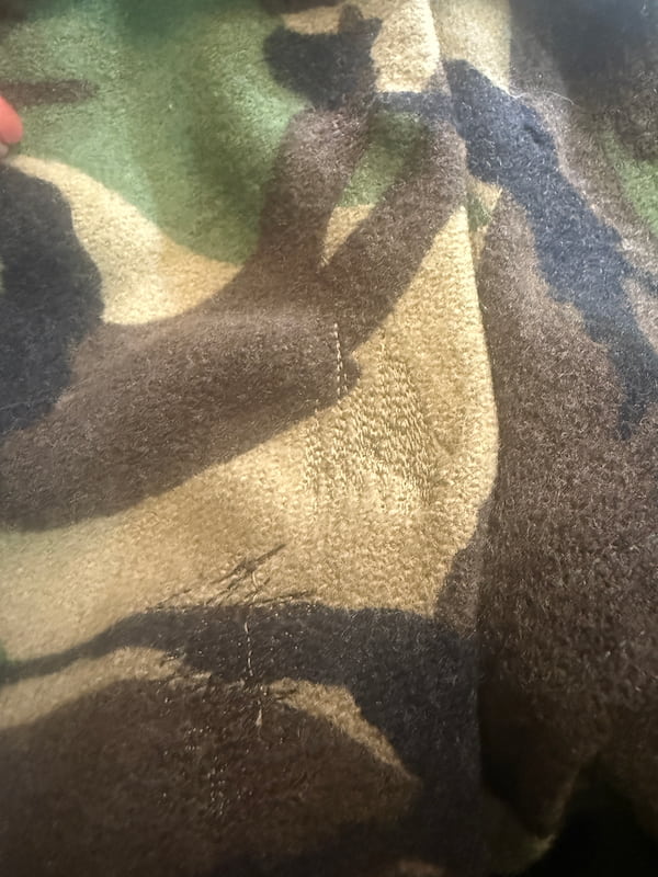 Close-up of a camouflage-patterned plush fabric with shades of brown, beige, green, and black.