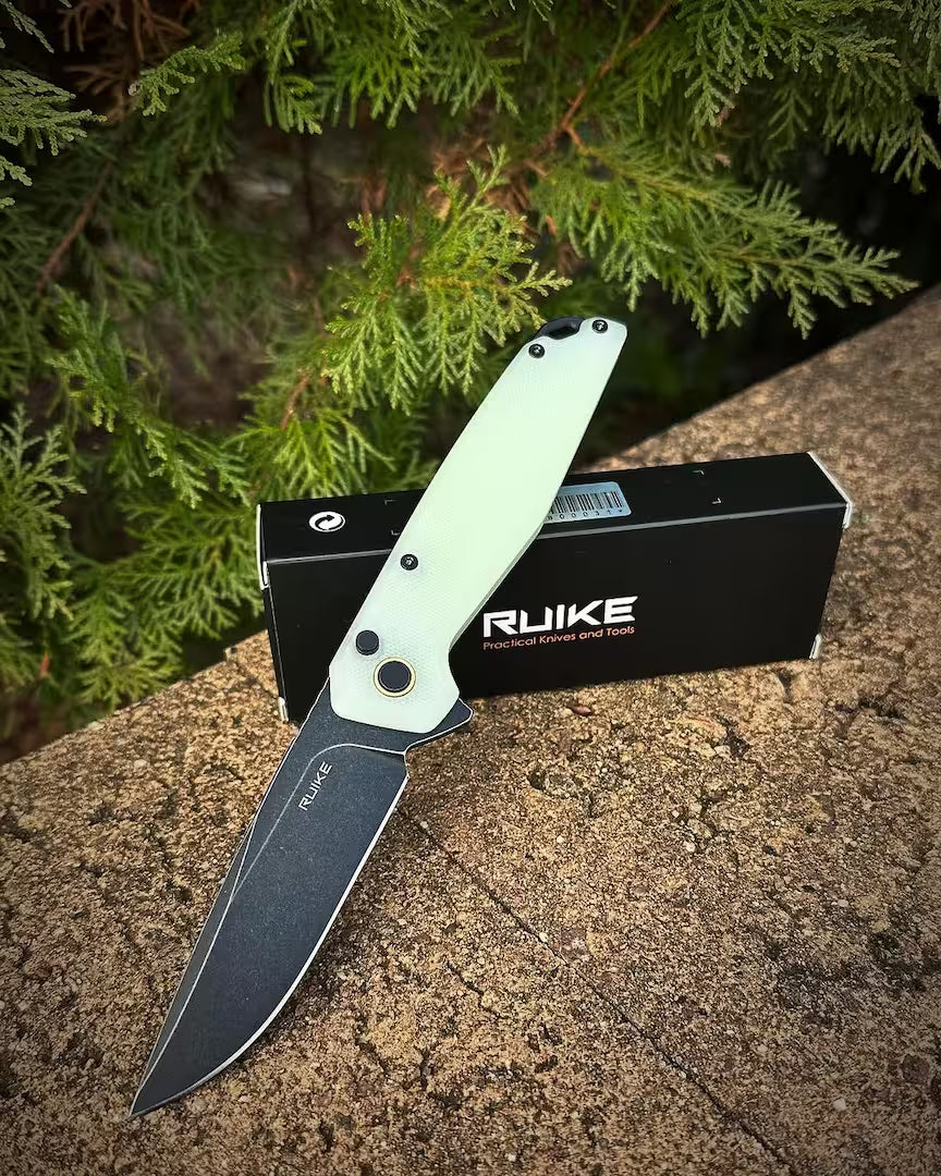 Folding knife with a green handle on a stone surface next to RUIKE packaging.
